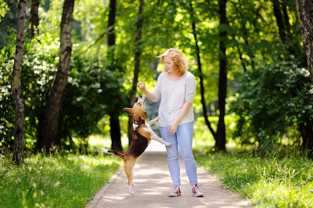 Młoda kobieta z Beagle psem w lato parku. Posłuszny zwierzak ze swoim właścicielem ćwiczący polecenie skoku