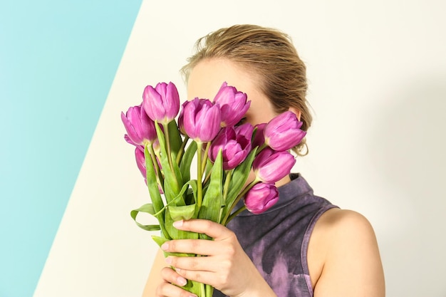 Młoda kobieta z bukietem pięknych liliowych tulipanów na jasnym tle koloru