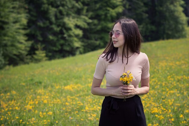 Młoda kobieta z bukietem polne kwiaty na słonecznym trawniku. Letni dzień