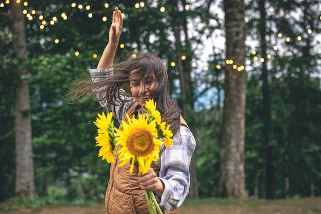 Młoda kobieta z bukietem słoneczników na rozmytym tle w naturze
