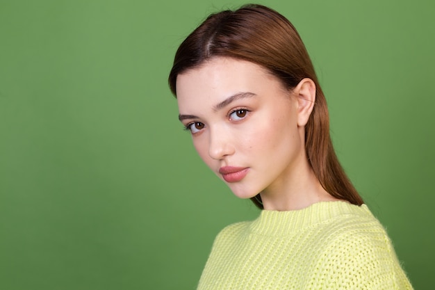 Młoda kobieta z czystą idealną naturalną skórą i makijażem brązowe duże usta na zielonej ścianie pozowanie