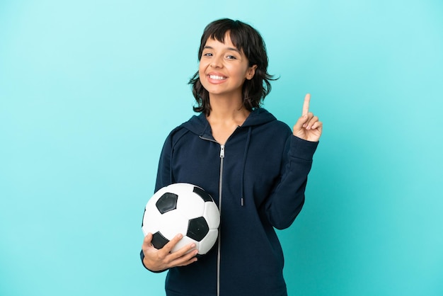 Młoda kobieta z drużyny futbolowej rasy mieszanej na białym tle na niebieskim tle pokazująca i unosząca palec na znak najlepszych