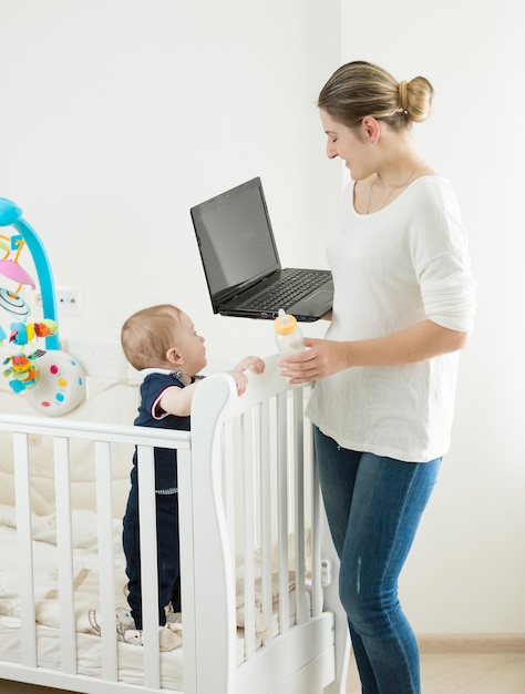 Młoda kobieta z dzieckiem pracuje w domu na laptopie