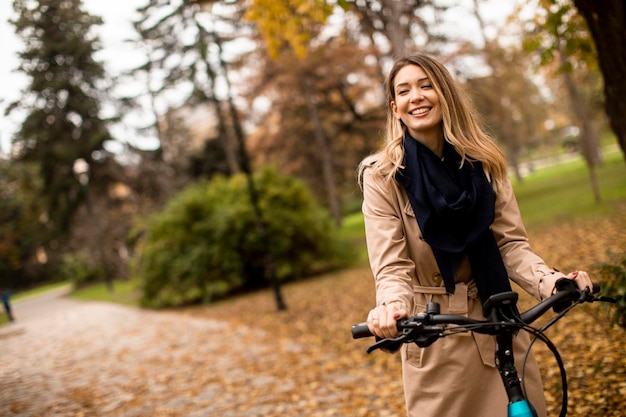 Młoda kobieta z elektrycznym rowerem w jesiennym parku