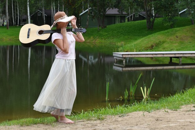 Młoda kobieta z gitarą na naturze