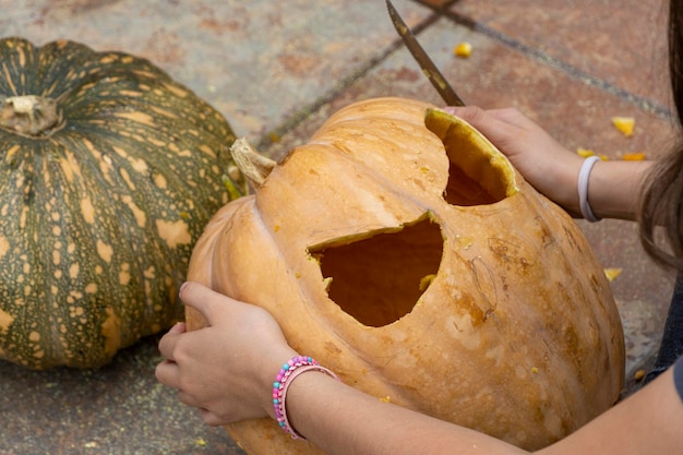 Młoda kobieta z głową dyni po odcięciu jej i nałożeniu na nią twarzy halloween