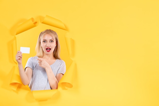 Zdjęcie młoda kobieta z kartą kredytową na żółtym tle pieniądze na zakupy twarzy