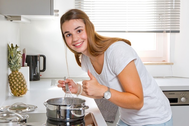 Zdjęcie młoda kobieta z kciukiem do góry gotuje