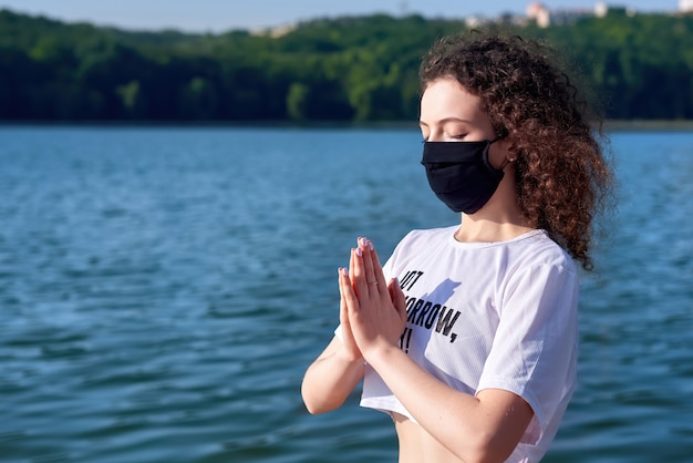 Młoda kobieta z kręconymi włosami robi joga na zewnątrz