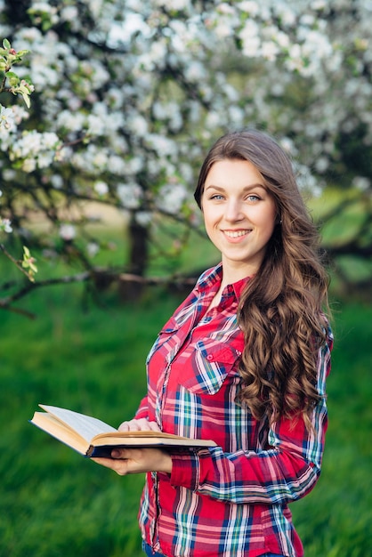 Młoda kobieta z książką w kwitnącym ogrodzie