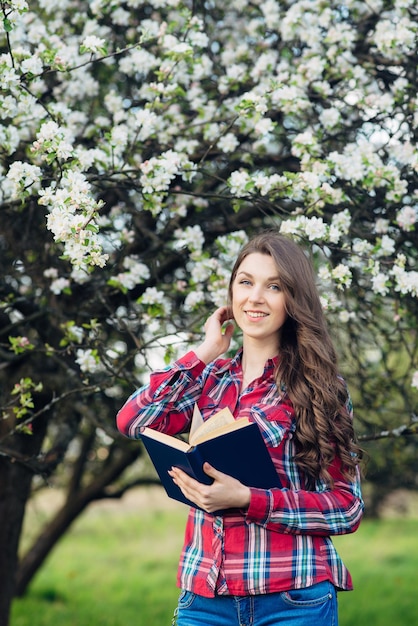Młoda kobieta z książką w kwitnącym ogrodzie