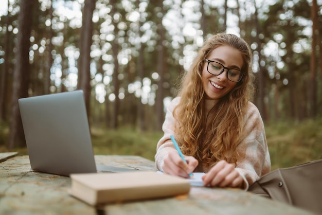 Młoda kobieta z laptopem pracująca lub studiująca online na świeżym powietrzu Business blogging video konferencja
