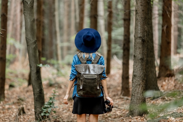 Młoda kobieta z lornetką i plecakiem w lesie
