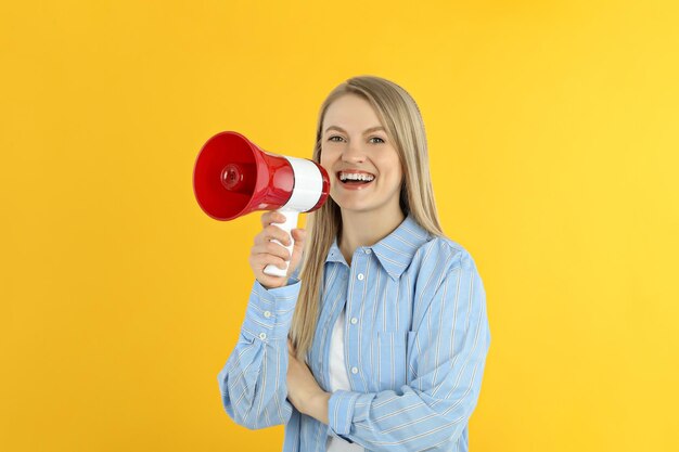 Młoda kobieta z megafonem na żółtym tle