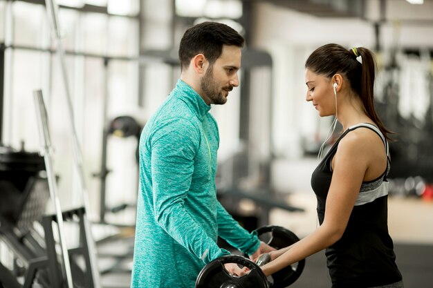 Młoda kobieta z osobistym trenerem w gym