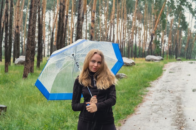 Zdjęcie młoda kobieta z parasolem stojąca w lesie