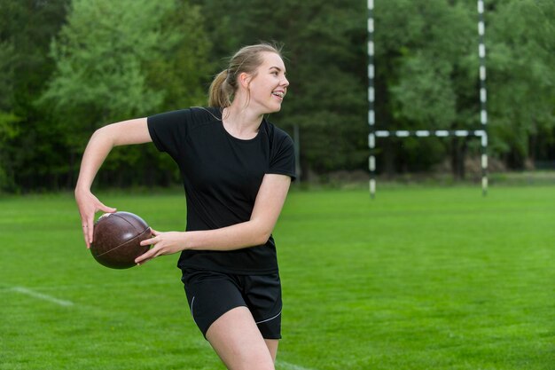 Zdjęcie młoda kobieta z piłką rugby grająca na boisku