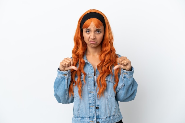 Zdjęcie młoda kobieta z pomarańczowymi włosami na białym tle pokazując kciuk w dół z dwiema rękami