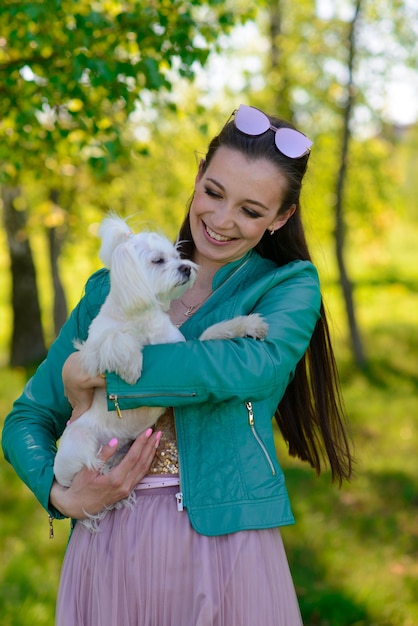 Młoda kobieta z psem. Biały szczeniak biegnie ze swoim właścicielem. Pojęcie o przyjaźni i zwierzęciu.