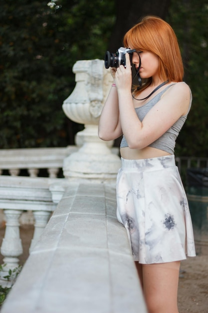 Młoda kobieta z retro kamerą w parku