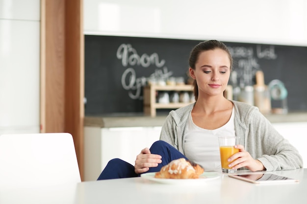 młoda kobieta z sokiem pomarańczowym i tabletką w kuchni