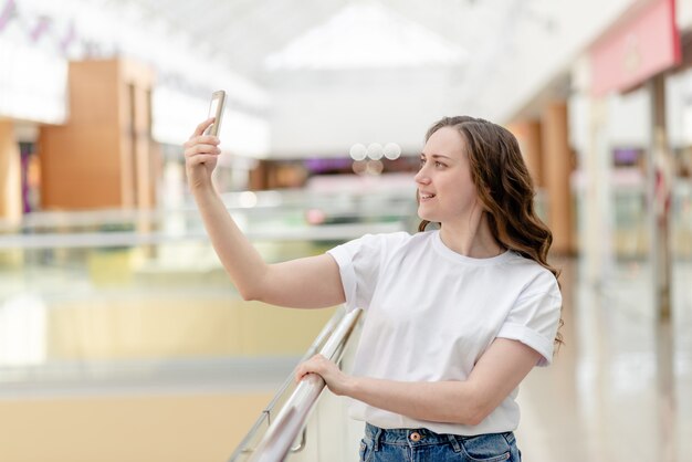 Młoda kobieta z telefonem w jej ręce robi selfie. Portret, szczęśliwy uśmiech, piękno i technologii pojęcie