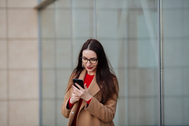 Młoda kobieta z torby podróżnej i inteligentny telefon spaceru na lotnisku dla turystyki podróżniczej.