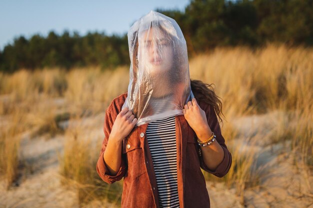 Zdjęcie młoda kobieta z twarzą pokrytą plastikową torbą stojąca na plaży