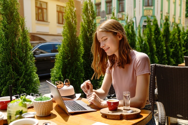 Młoda kobieta za pomocą laptopa w kawiarni na letnim tarasie