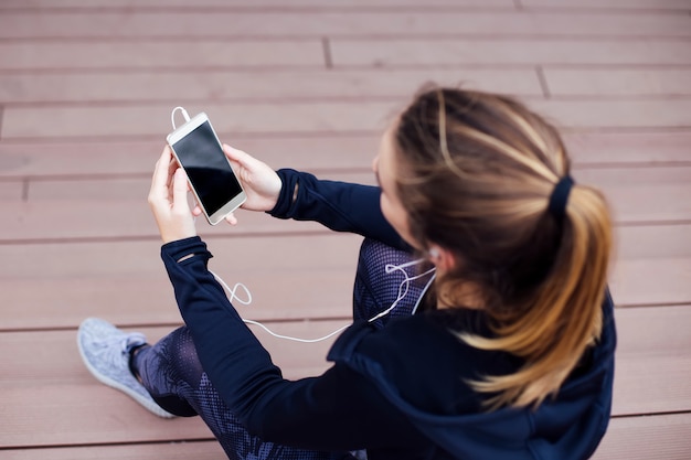 Młoda Kobieta Za Pomocą Telefonu Komórkowego I Sittinng Na Schodach