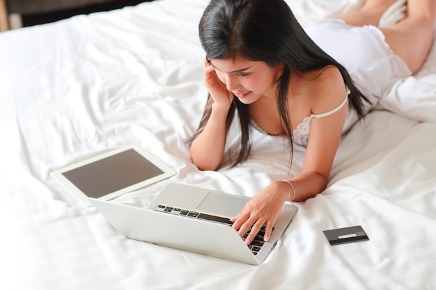 młoda kobieta zakupy i płatności online za pomocą laptopa w sypialni