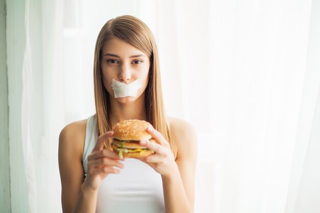 Młoda kobieta zapobiega jej jeść fast foodów. Koncepcja zdrowego odżywiania