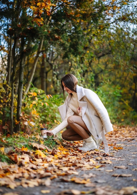Młoda kobieta zbierająca upadłe liście w parku