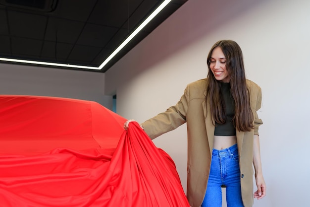 Młoda kobieta zdejmuje materiał ze swojego nowego samochodu w salonie sprzedaży