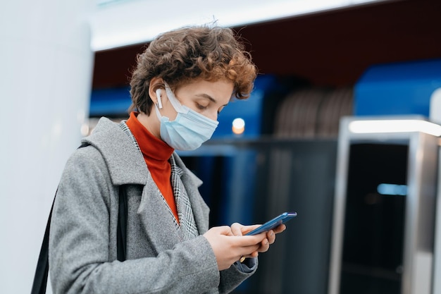 Młoda kobieta ze smartfonem stojąca w metrze