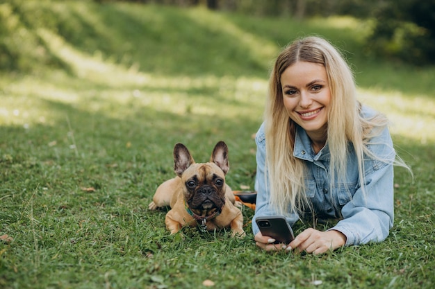 Młoda kobieta ze swoim zwierzakiem buldogiem francuskim w parku