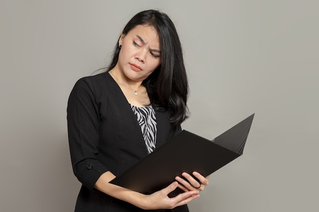 Młoda kobieta ze zdumionym wyrazem twarzy trzymająca folder, patrząc wstecz