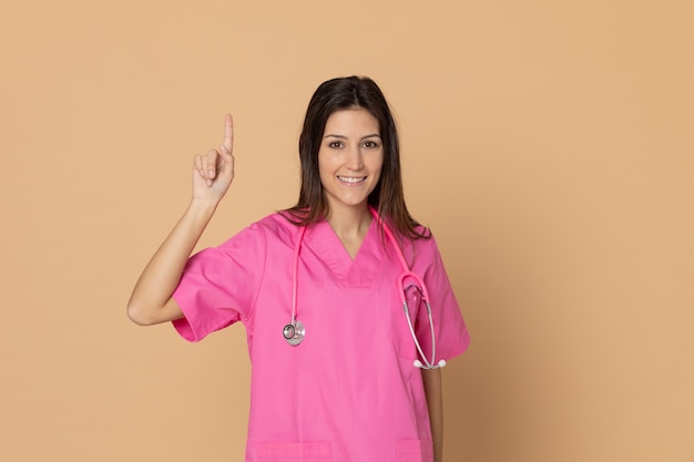 Młoda kobiety lekarka gestykuluje nad brąz ścianą z różowym mundurem
