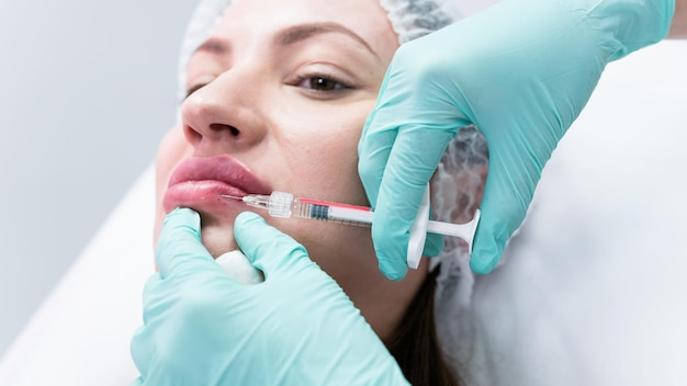 Młoda kosmetyczka przygotowuje się do wykonania zastrzyku w usta kobiety