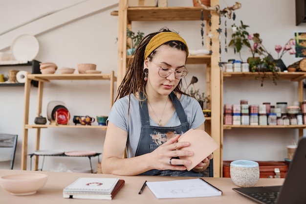 Młoda kreatywna bizneswoman w casualwear trzymająca ceramiczny przedmiot