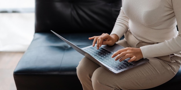 Młoda ładna Azjatka Korzysta Z Laptopa Siedząc Na Kanapie W Salonie