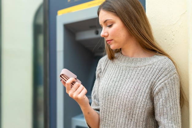 Młoda ładna blondynka za pomocą bankomatu