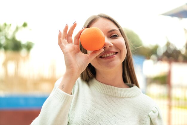 Młoda ładna blondynki kobieta trzyma pomarańczę z szczęśliwym wyrażeniem