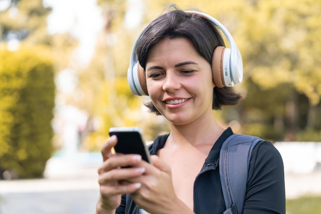 Młoda ładna Bułgarka na świeżym powietrzu przy użyciu telefonu komórkowego