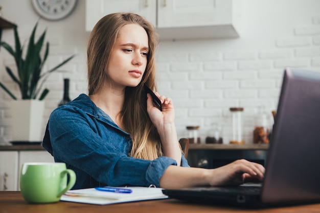 Młoda ładna dziewczyna w ciąży pracuje w domu w trybie samoizolacji w kwarantannie i dokonuje zakupów online