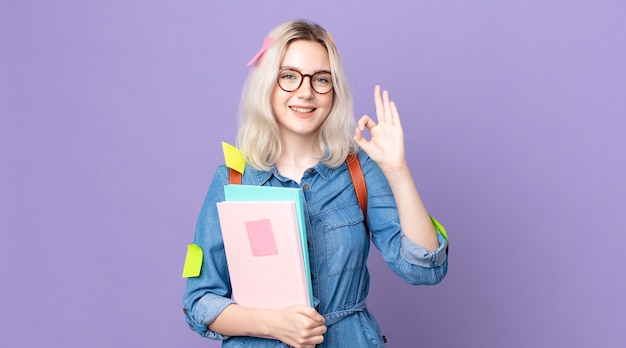 Młoda ładna kobieta albinos czuje się szczęśliwa, pokazując aprobatę w porządku gestem. koncepcja studenta