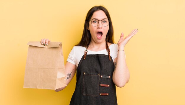 Młoda ładna kobieta czuje się szczęśliwa i zdumiona czymś niewiarygodnym kurierem fast food