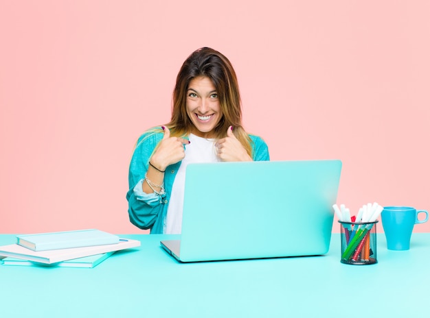 Młoda ładna kobieta pracująca z laptopem czuje się szczęśliwa, zaskoczona i dumna, wskazując na siebie z podekscytowanym, zdumionym spojrzeniem