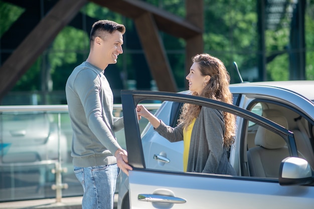 Młoda ładna kobieta rozmawia z wysokim mężczyzną stojącym w pobliżu samochodu