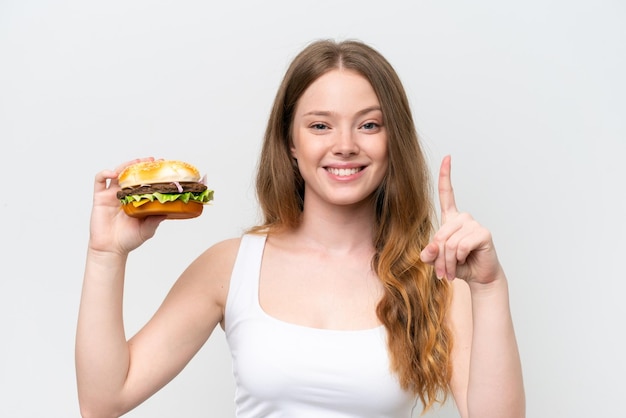 Młoda ładna kobieta trzyma burgera odizolowanego na białym tle, wskazując świetny pomysł